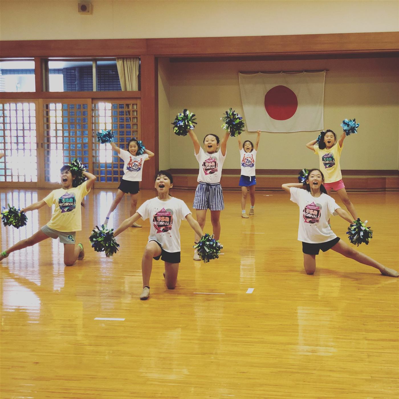 体育館でポンポンを持って練習する小学生メンバー